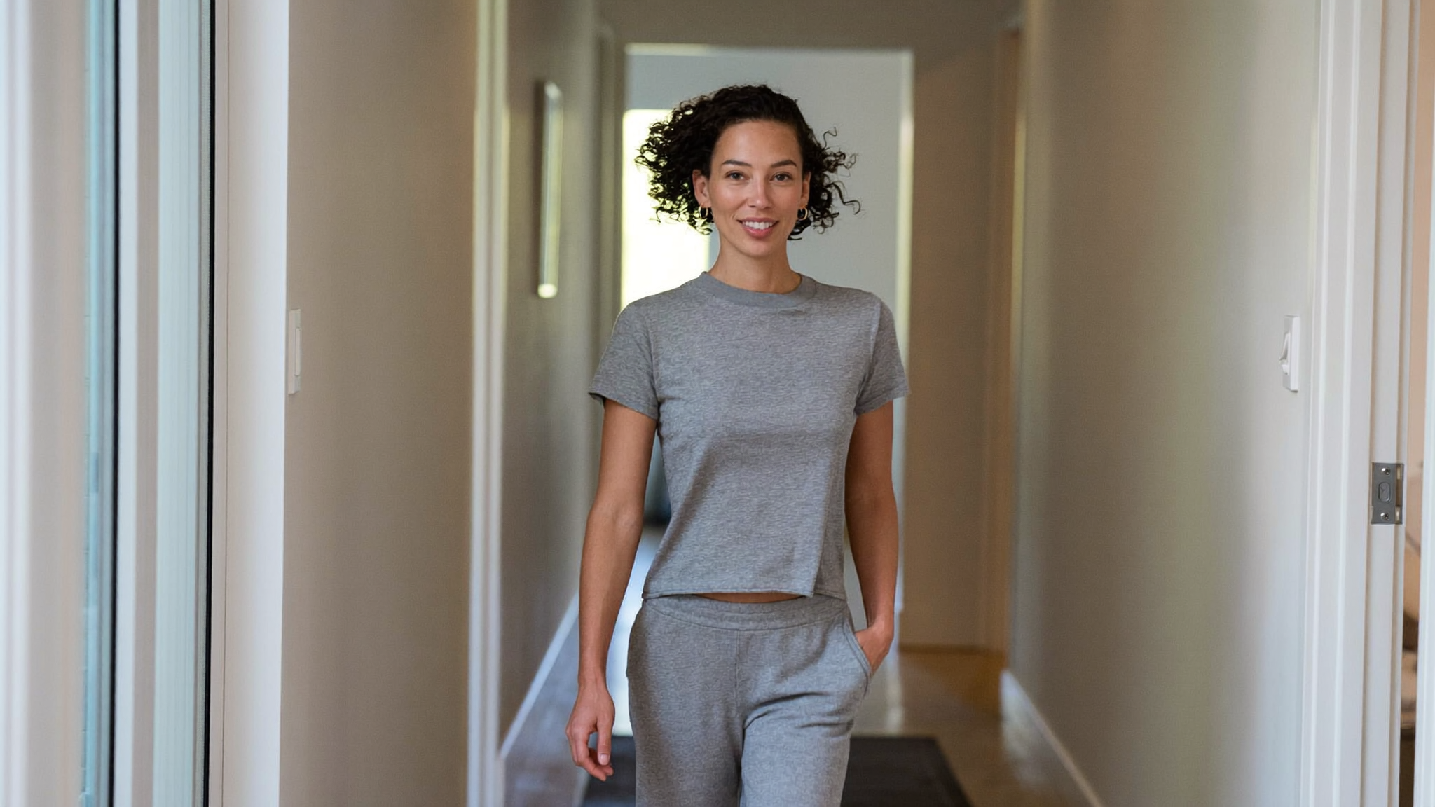 A confident mother walking through a bright modern home, at ease