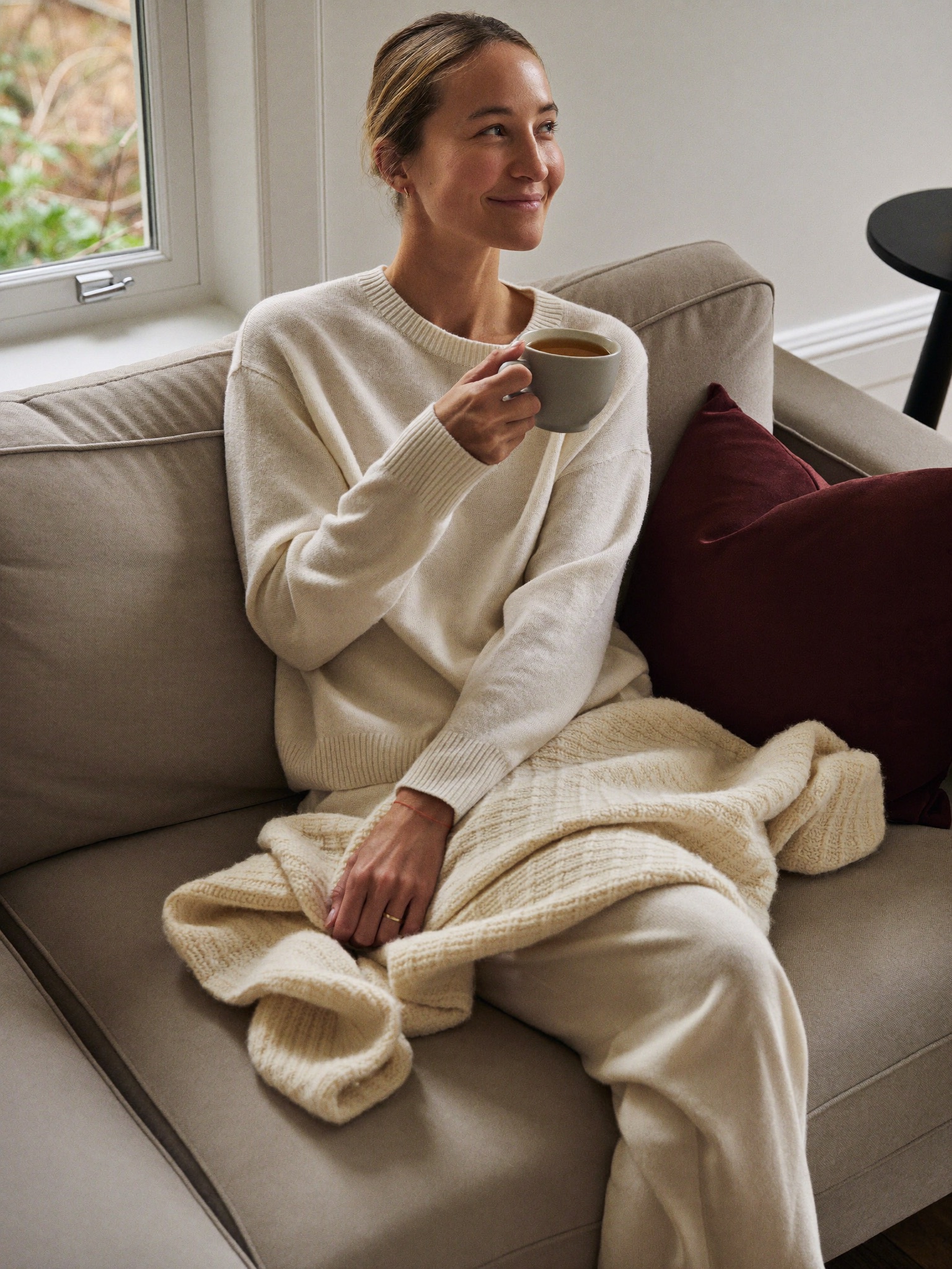 A mother resting comfortably at home with a warm cup of tea, unhurried and at ease