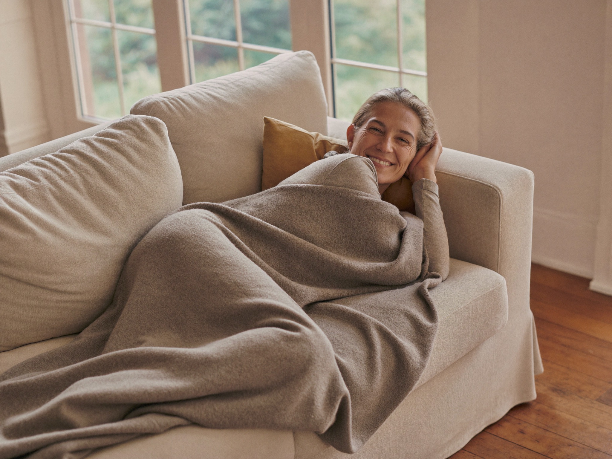 A mother resting comfortably at home, wrapped in a blanket, completely at ease