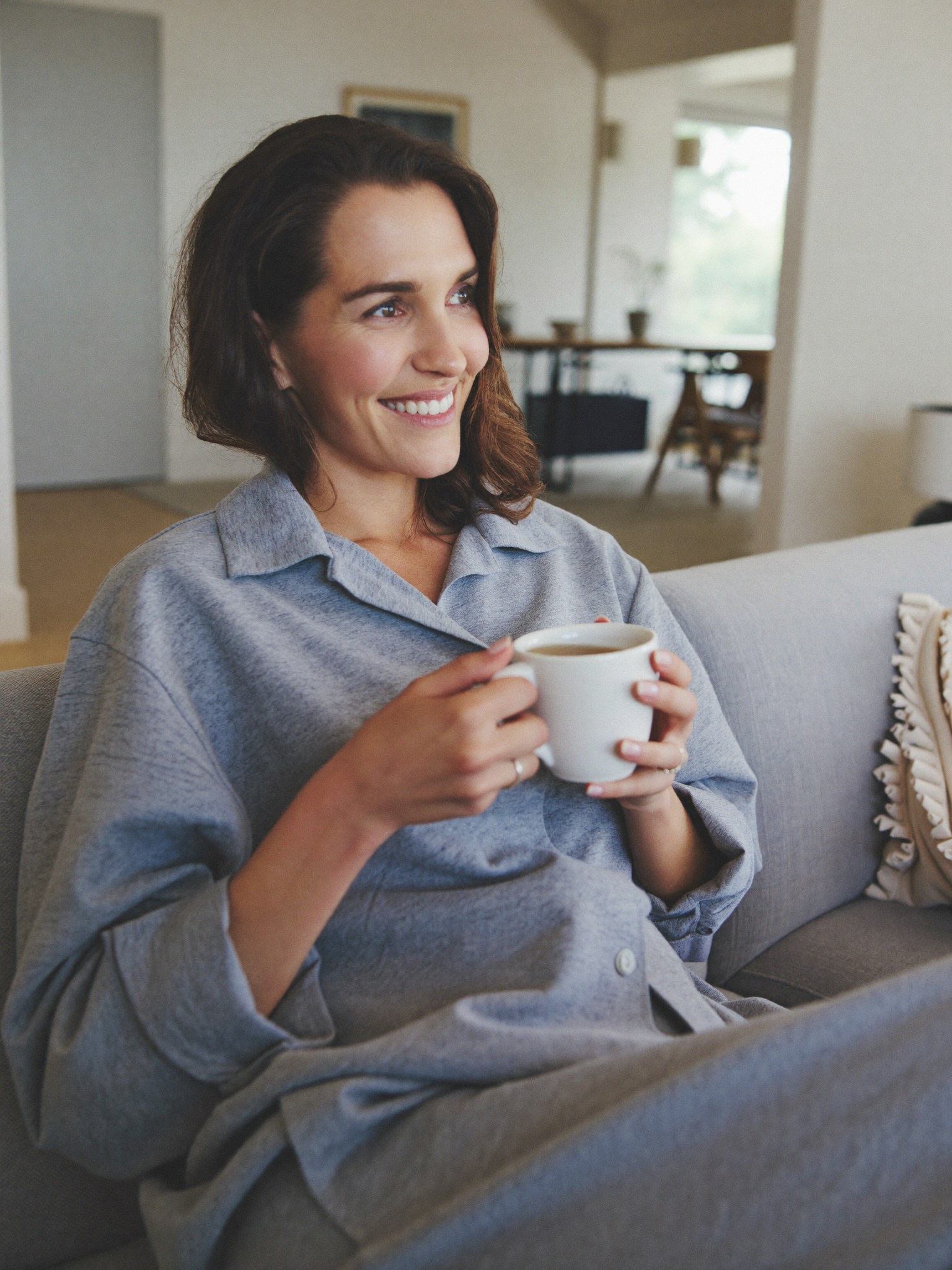 A relieved mother relaxing at home with a warm drink, at ease about her financing plan