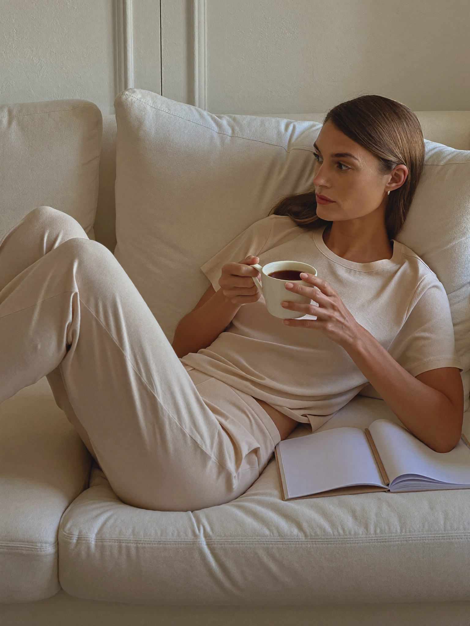 A mother relaxed at home with a warm drink, unhurried and at ease about the timing